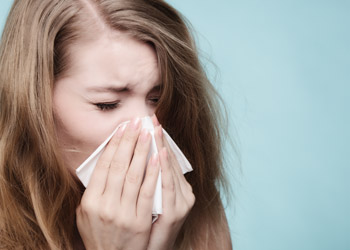 Woman sneezing after contracting the flu in the workplace