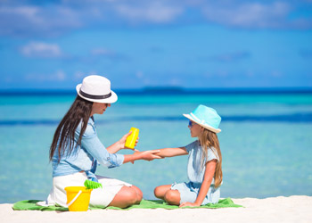 Mother applying sunscreen to her daughter on the beach