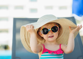 Little girl wearing a wide-brim hat and sunglasses